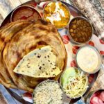 A vibrant plate of Amritsari kulcha served with chole and topped with butter.