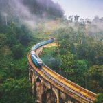 A solo backpacker walking on a scenic mountain trail, illustrating how to travel on a budget.
