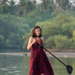A solo female traveler enjoying the sunset on a quiet beach in Goa, walking towards the ocean with her arms outstretched.