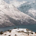 A snowy mountain landscape in Queenstown, New Zealand, with a ski resort and clear blue sky.
