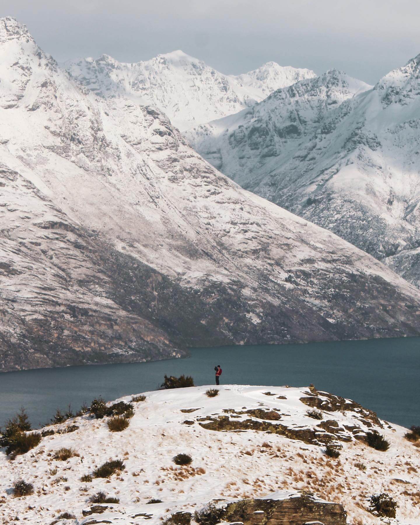 A snowy mountain landscape in Queenstown, New Zealand, with a ski resort and clear blue sky.