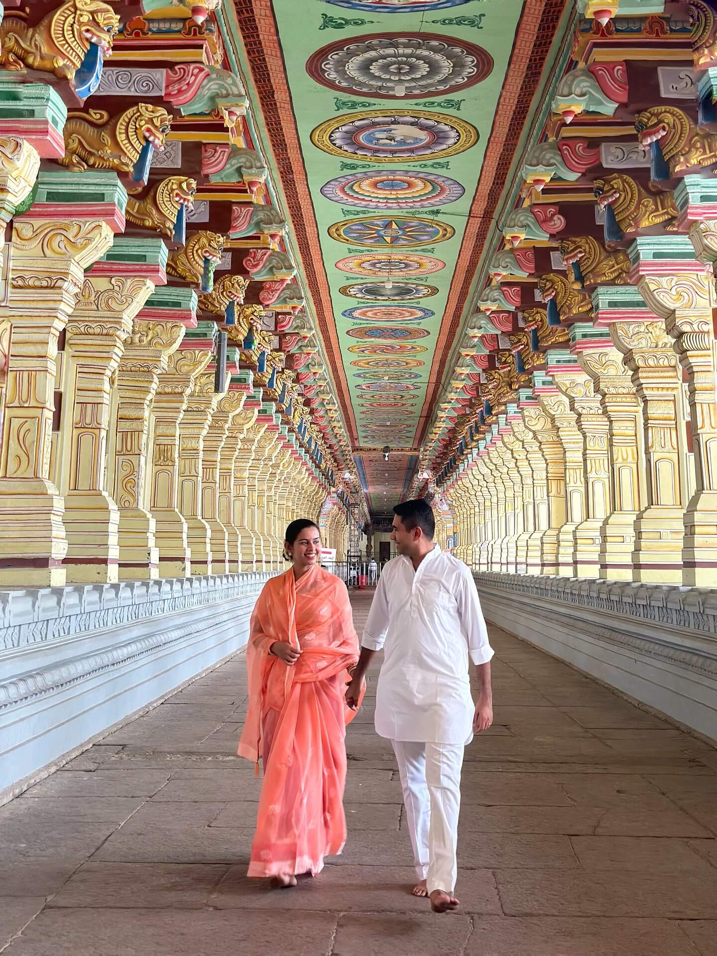 The long, highly ornate corridor of the Ramanathaswamy Temple in Rameswaram, Tamil Nadu, lined with intricately carved stone pillars.