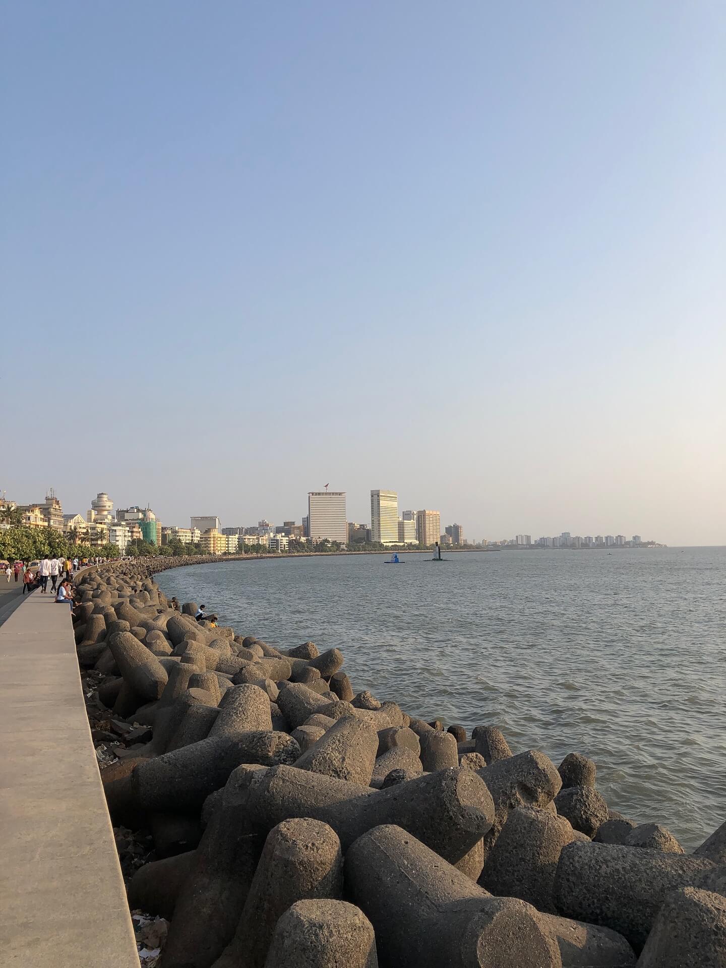 A high-angle, nighttime view of Marine Drive in Mumbai, showing the curved sea-facing promenade brilliantly lit up, resembling a 'Queen's Necklace.