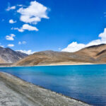 "A stunning view of Ladakh's rugged mountains and a serene turquoise lake."
