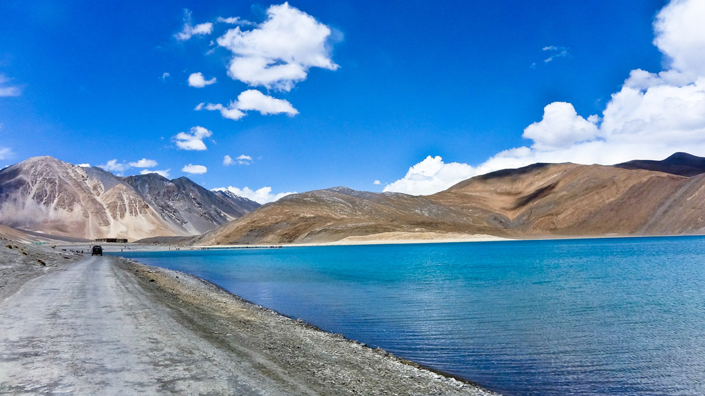 "A stunning view of Ladakh's rugged mountains and a serene turquoise lake."
