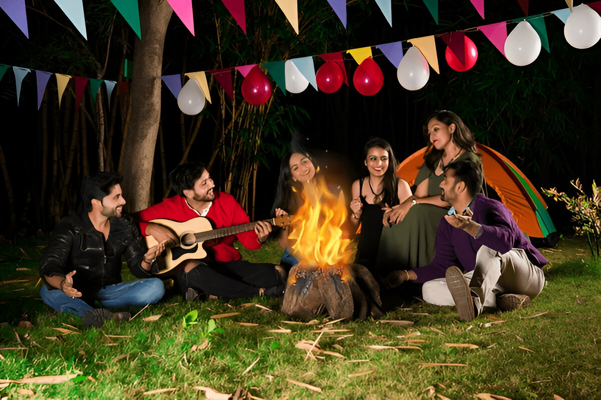 A vibrant image of a campfire under a starry night sky with tents pitched in the background