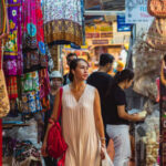 A bustling aerial or wide shot of Chatuchak Weekend Market in Bangkok, Thailand, showing countless stalls with colorful awnings, crowded pathways, and a diverse array of goods for sale. Thailand Trip 2026
