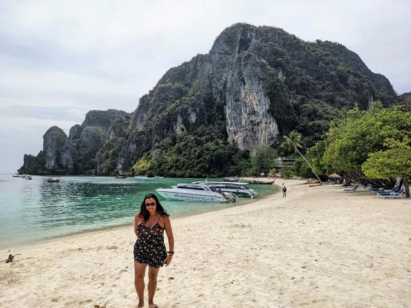 An aerial view of Koh Phi Phi Don, Thailand, showcasing its unique "H" shape with two main landmasses connected by a narrow sandy isthmus, flanked by turquoise bays and surrounded by lush green cliffs.