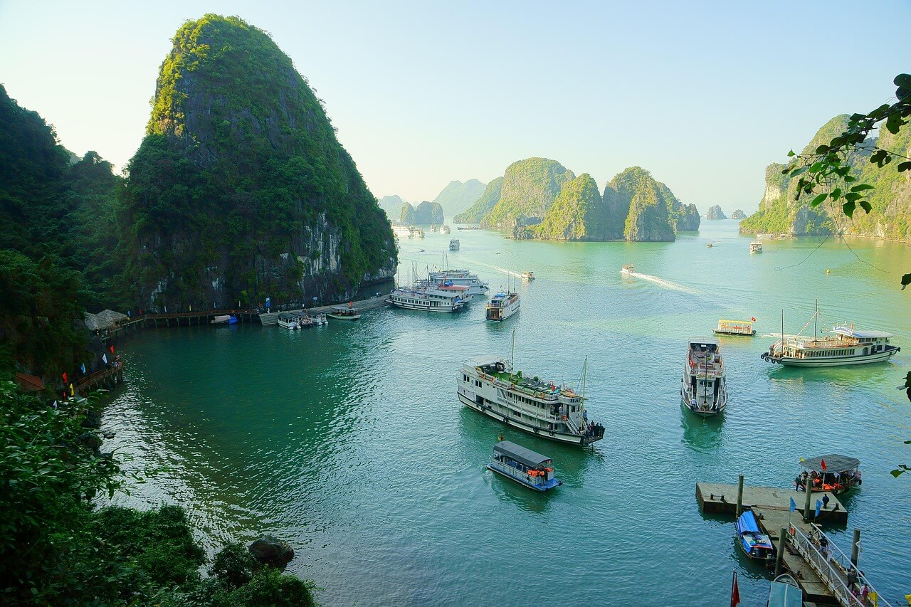 "A vibrant collage showcasing iconic Vietnamese experiences: the stunning limestone karsts of Halong Bay with a traditional boat, a bustling street scene in Hanoi with colorful lanterns, the intricate terraced rice fields of Sapa, and the unique Golden Bridge in Da Nang. The image conveys a sense of adventure and the diverse beauty of an amazing Vietnam tour."