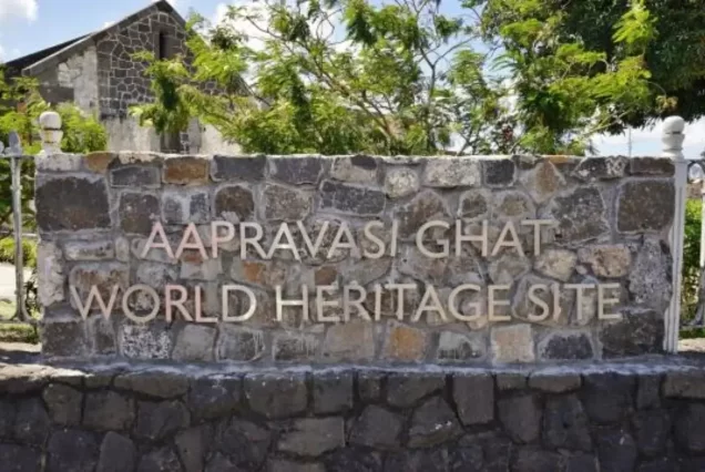 An exterior shot of the Aapravasi Ghat Museum, a historic stone building with a small arched entryway, located on the harbor of Port Louis.