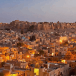 A beautiful sunset over the sand dunes of Jaisalmer, with several luxury tents set up for a desert camp, one of the best camping spots for nature lovers in India.