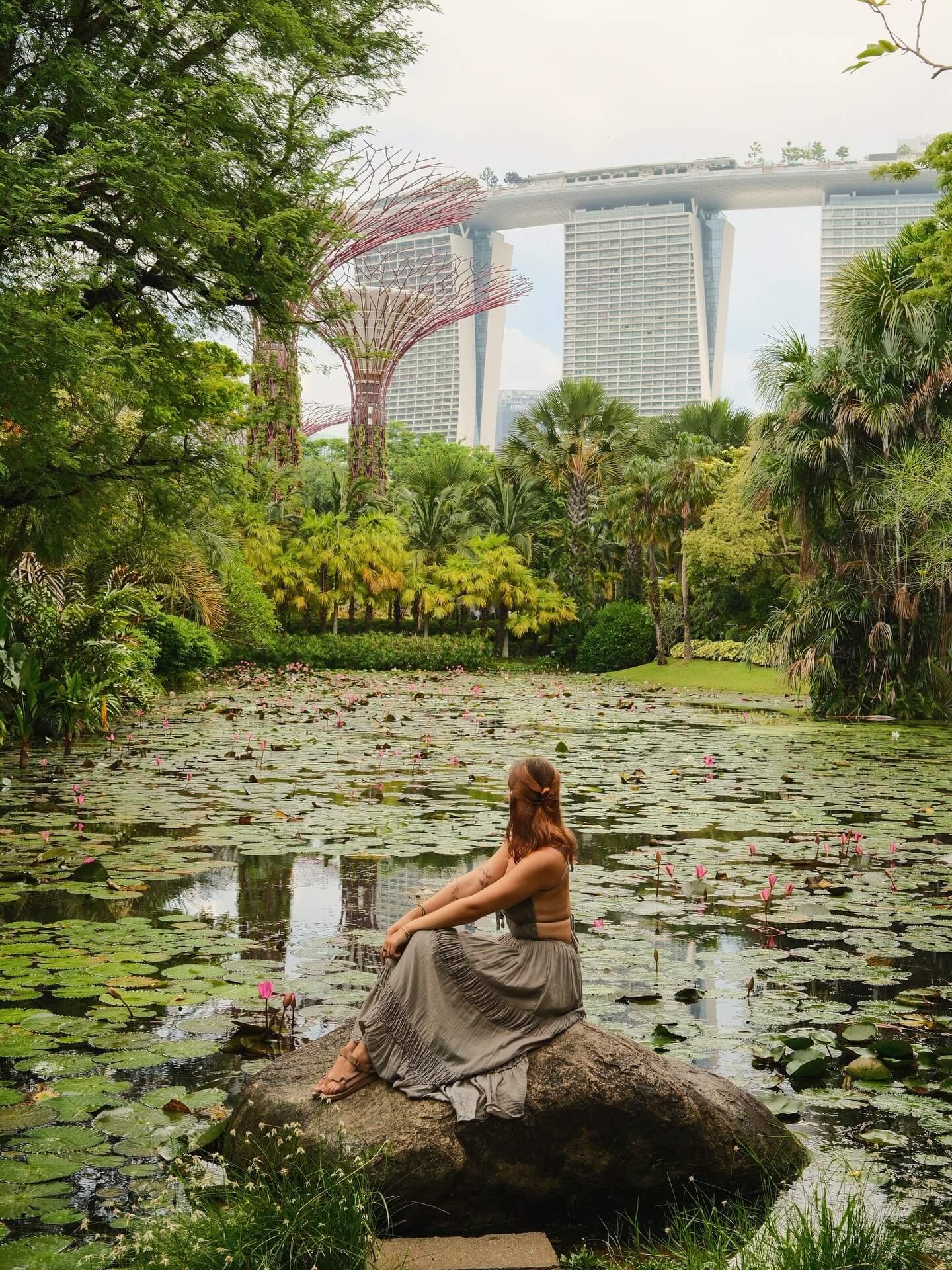 "Split image showing the modern, illuminated skyline of Singapore on one side and a tranquil, sunset beach scene in Bali with a couple, representing a dual-destination honeymoon."