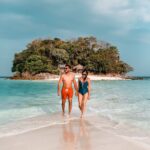 A narrow sandbar connecting Tup Island and another small island in Krabi, Thailand, surrounded by clear turquoise water, with lush green islands in the background.