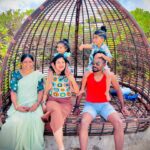 A photograph of a family of four, including two parents and two children, laughing and posing for a selfie during their vacation.