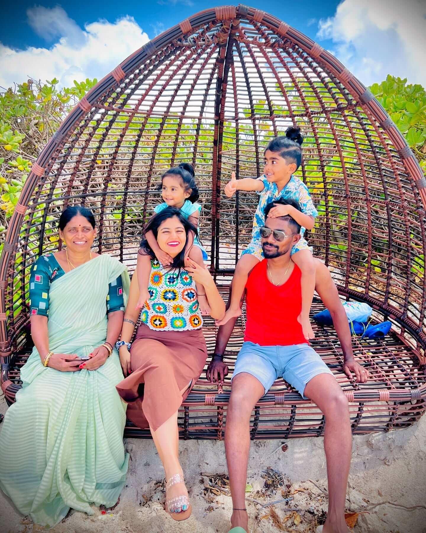 A photograph of a family of four, including two parents and two children, laughing and posing for a selfie during their vacation.