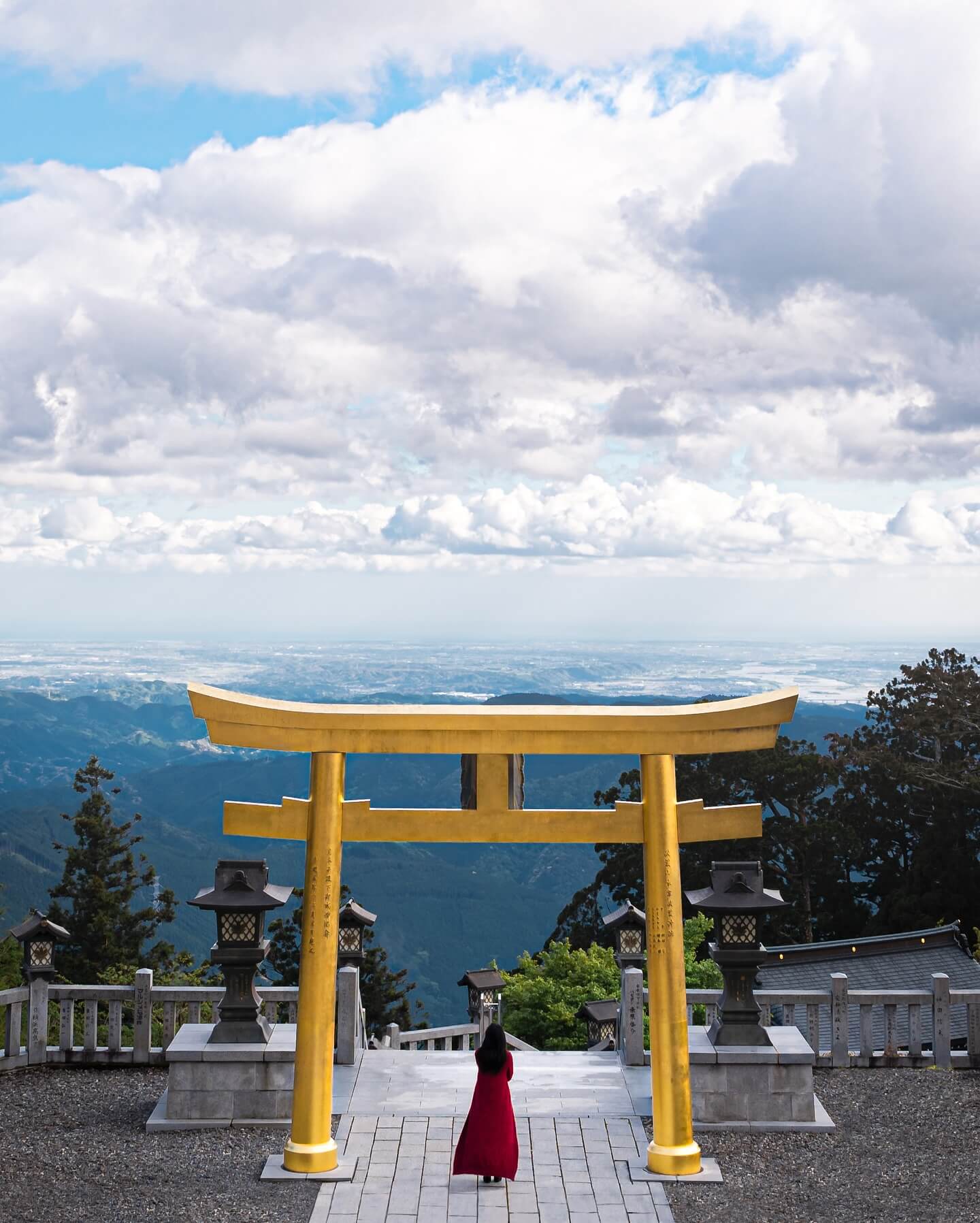 A scenic photograph of a lake with the iconic Mount Fuji in the background, a row of traditional Japanese pagodas, and cherry blossoms in full bloom in the foreground.