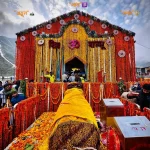 Best time to visit Kedarnath during temple season, showing devotees praying at the Kedarnath Temple beautifully decorated with marigold flowers against the Himalayan mountains.