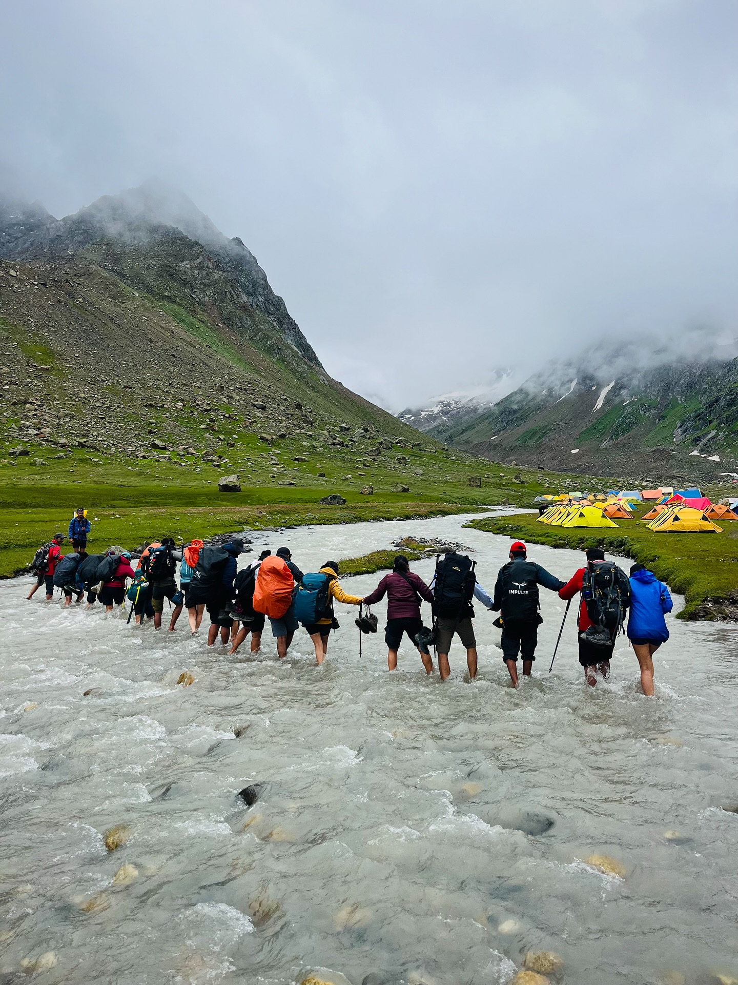 River crossing during Hampta Pass trek with hikers walking through water