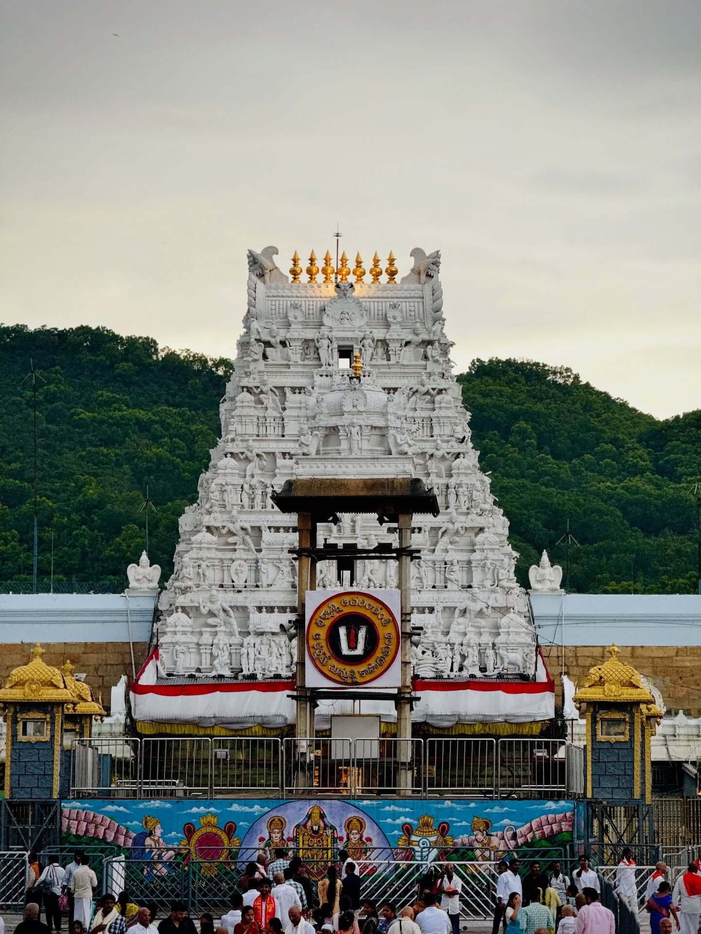 A beautiful view of the sacred Tirumala Venkateswara Temple in Tirupati with devotees standing in line for darshan, surrounded by hills and spiritual ambiance in Andhra Pradesh.
