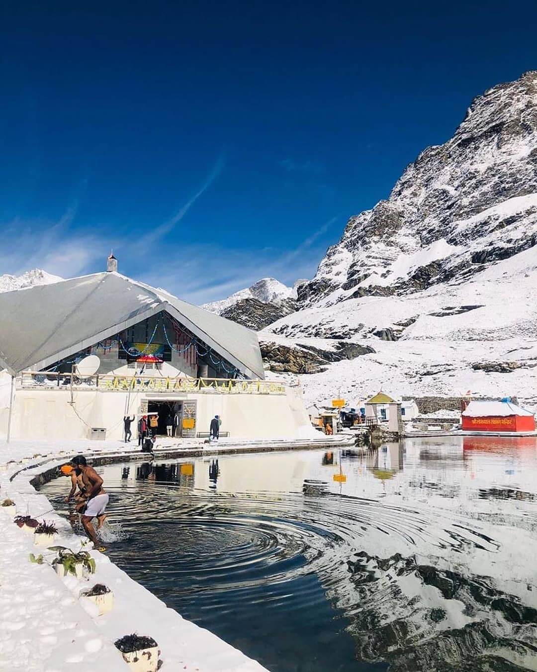 Trekkers and pilgrims walking on the Hemkund Sahib Trek route surrounded by Himalayan mountains and waterfalls